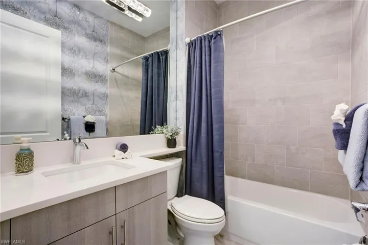 Full bath with vanity, toilet, and shower / bath combo with shower curtain