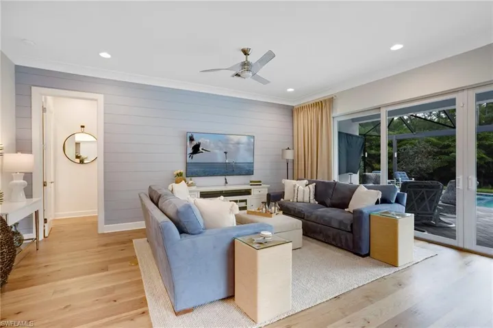 Living area featuring light wood-style floors, a ceiling fan, ornamental molding, recessed lighting, and baseboards