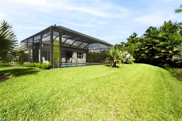 View of green lawn featuring an outdoor pool and a lanai