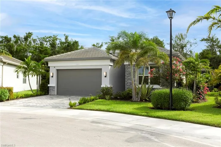 View of front of home featuring a garage, stucco siding, decorative driveway, a front yard, and stone siding