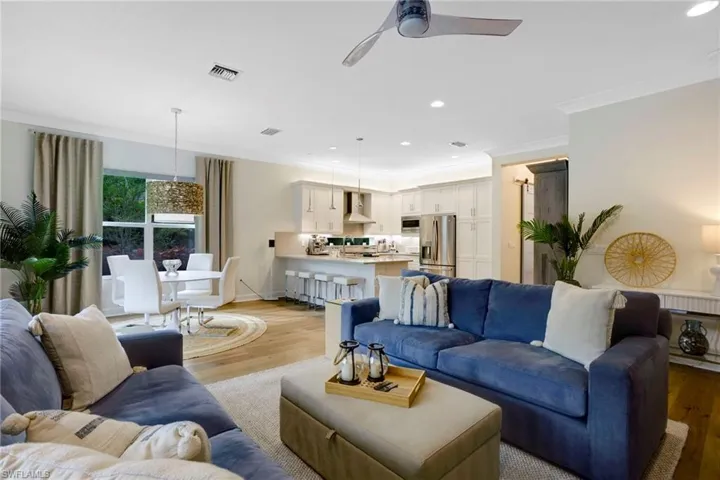 Living room with recessed lighting, crown molding, ceiling fan, light wood finished floors, and baseboards