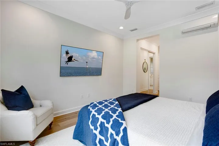 Bedroom featuring a wall unit AC, wood finished floors, baseboards, a ceiling fan, and recessed lighting