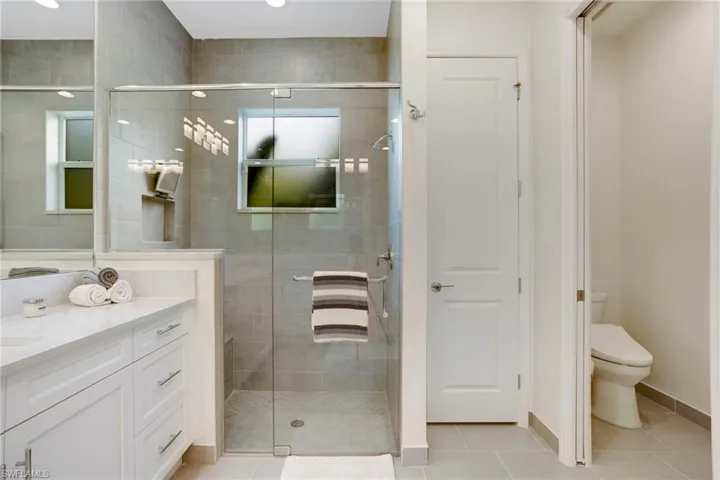 Full bath featuring vanity, tile patterned floors, toilet, and a shower stall