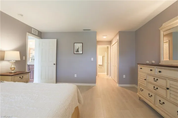 Bedroom with ensuite bathroom, light wood-type flooring, and a closet