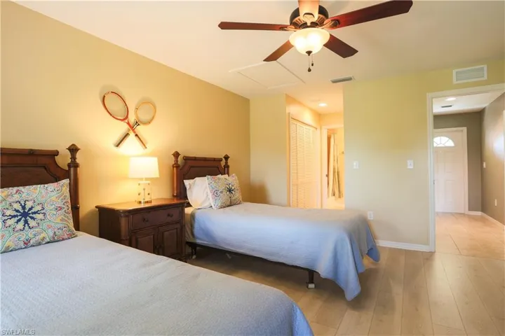 Bedroom featuring light wood-type flooring, a ceiling fan, a closet, and attic access