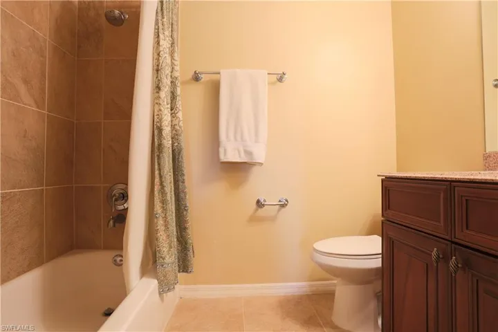 Full bath with shower / tub combo with curtain, vanity, and light tile patterned flooring