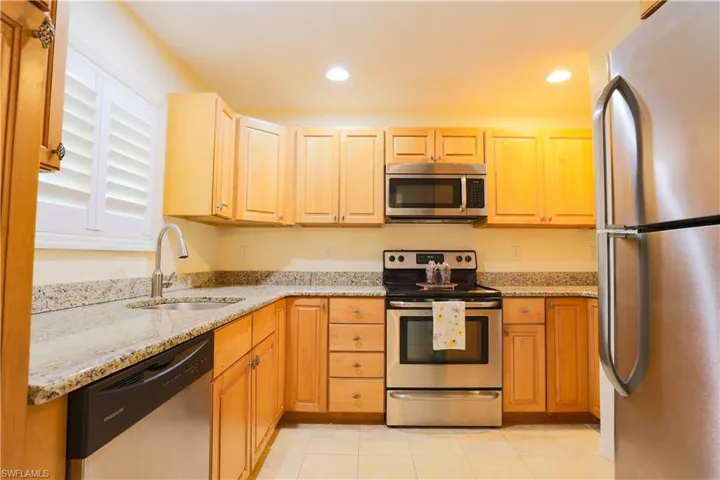 Kitchen featuring stainless steel appliances, light stone countertops, recessed lighting, and light tile patterned floors