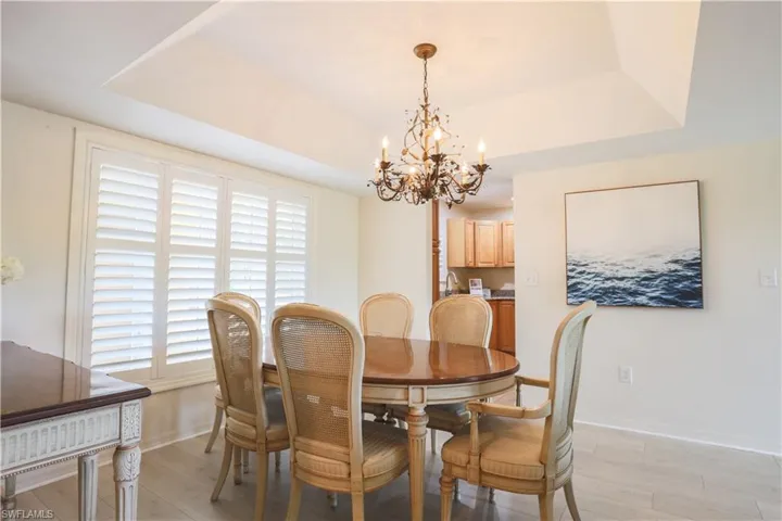 Dining room featuring a tray ceiling, light wood-type flooring, and a chandelier