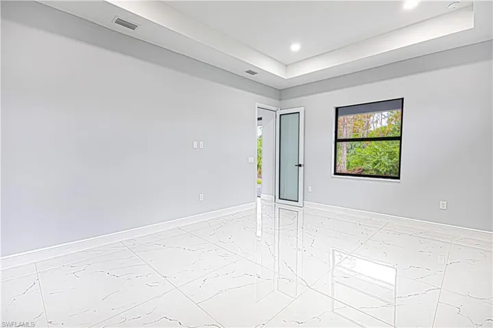 This bright interior space features large format tile flooring, a window offering views of greenery, and a ceiling with recessed lighting