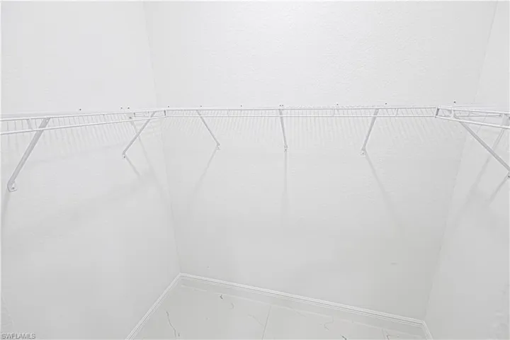 Spacious closet with white wire shelving and light-colored tile flooring