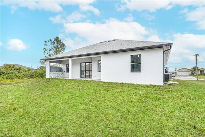 The property features a spacious yard with a lush lawn and an outdoor covered patio area