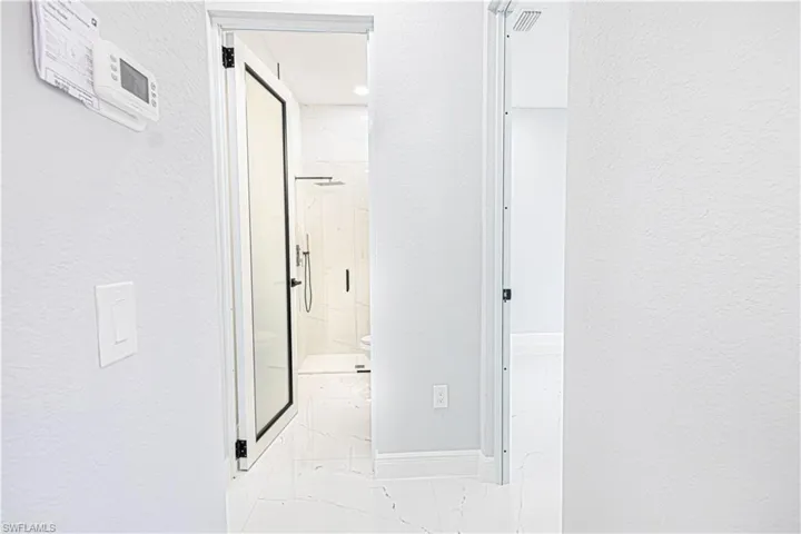 Bathroom featuring a glass shower enclosure with matte black fixtures and white marble-look tile flooring