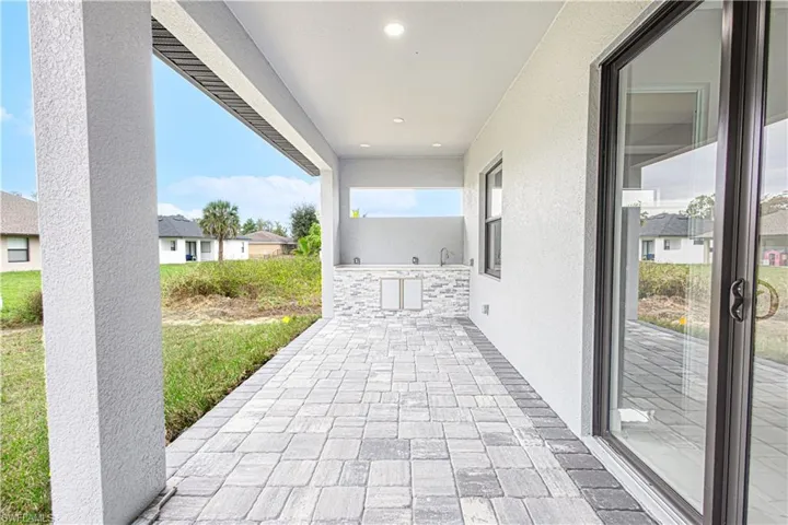 The property features a covered patio with an outdoor kitchen area, complete with a sink and storage