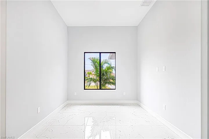 This room features a window providing a view of outdoor greenery, light-colored walls, and a tiled floor