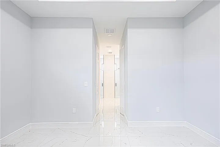 This interior space features light-colored walls and white trim, complemented by white tile flooring with a marbled pattern
