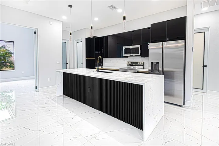 The kitchen features a large island with a waterfall countertop, sleek black cabinetry, and stainless steel appliances