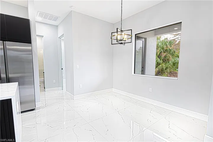 This bright interior features white tile flooring, a contemporary ceiling light fixture, and a window offering a view of greenery