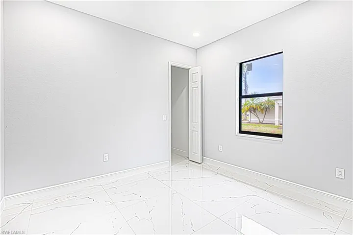 This room features sleek tile flooring, a window offering views of greenery, and a white bi-fold door