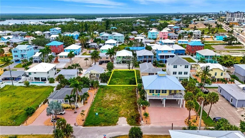 Aerial view of residential area featuring property parcel outlined and a large body of water - Virtually Edited Image
