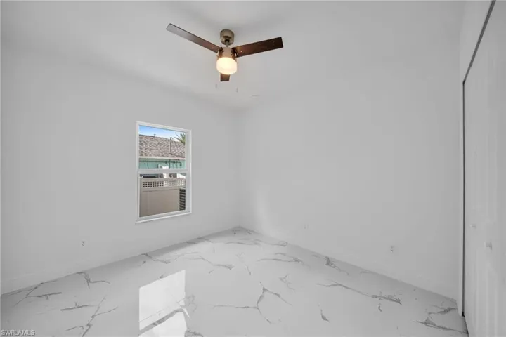 Spare room featuring marble finish floors and ceiling fan