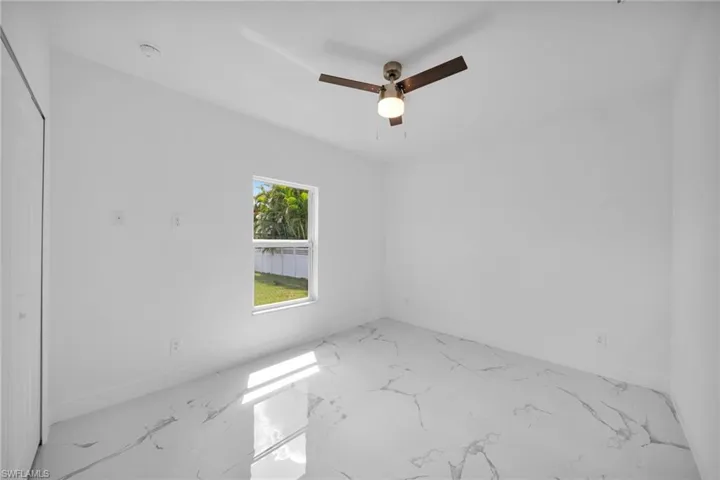 Spare room featuring marble finish floors and a ceiling fan