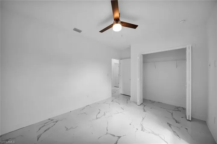 Unfurnished bedroom with a closet, marble finish flooring, and a ceiling fan