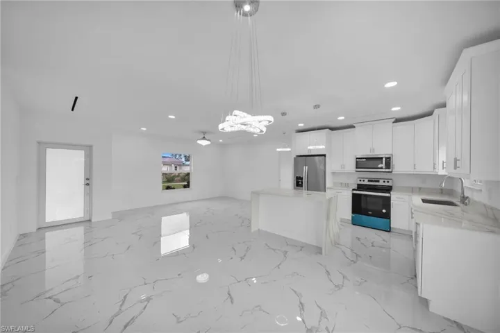 Kitchen featuring stainless steel appliances, recessed lighting, open floor plan, white cabinetry, and a kitchen island