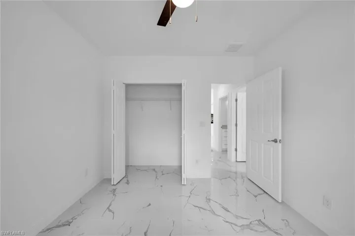 Unfurnished bedroom featuring marble finish floors, a closet, and ceiling fan