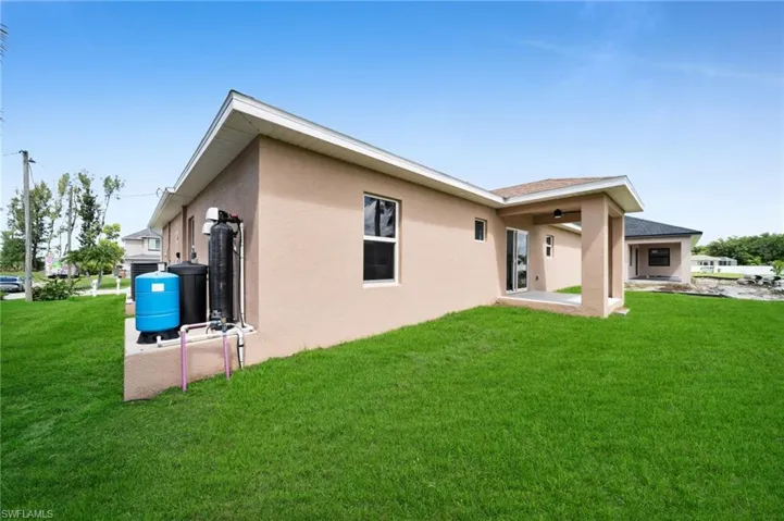 Rear view of house featuring stucco siding and a lawn