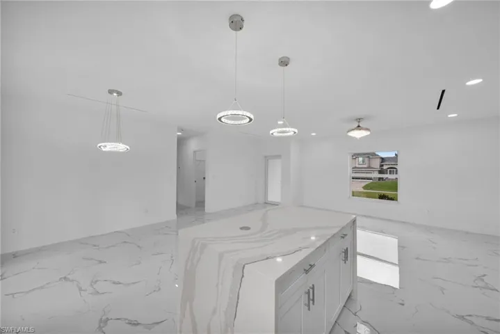 Kitchen featuring light marble finish flooring, open floor plan, white cabinetry, and recessed lighting