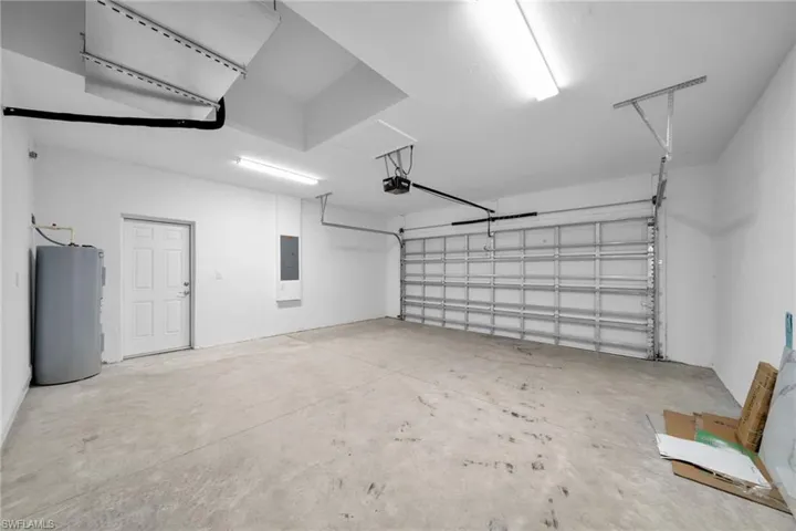 Garage with water heater, electric panel, and a garage door opener