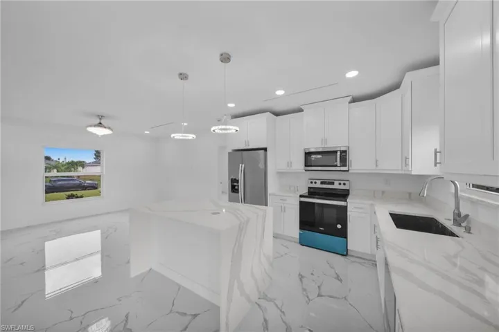 Kitchen featuring stainless steel appliances, recessed lighting, light stone counters, light marble finish floors, and white cabinetry