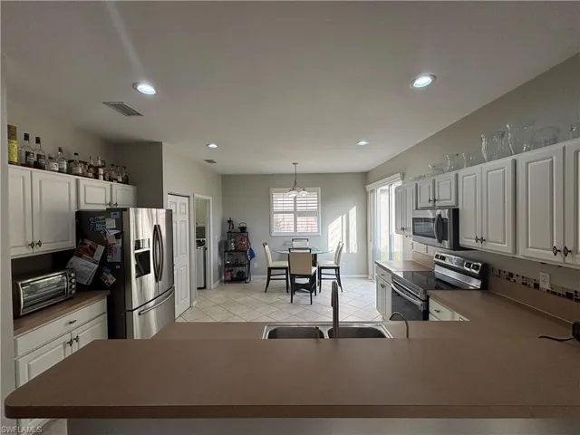 Kitchen with white cabinetry, stainless steel appliances, hanging light fixtures, recessed lighting, and a peninsula