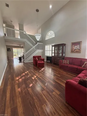 Living room with stairway, a high ceiling, and dark wood-type flooring