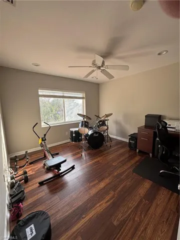 Exercise area featuring dark wood-type flooring, recessed lighting, and a ceiling fan