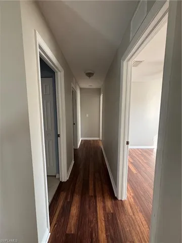 Hall featuring dark wood-style floors and baseboards