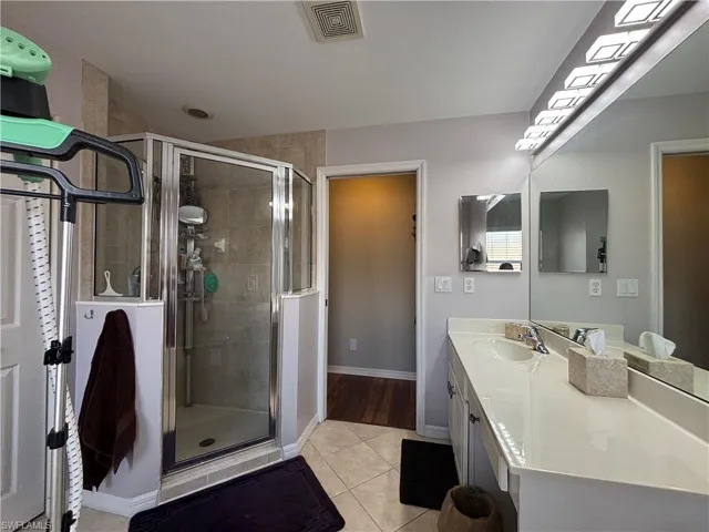 Bathroom featuring light tile patterned flooring, vanity, and a stall shower