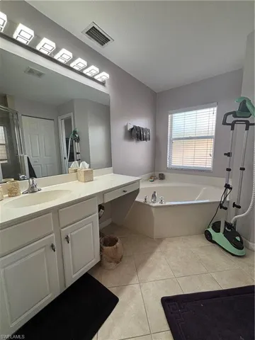 Bathroom featuring a bath, vanity, light tile patterned floors, and a shower stall