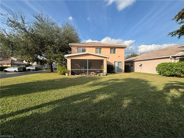 Back of house featuring a yard, a sunroom, and stucco siding