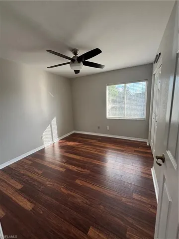 Spare room featuring dark wood-style flooring and a ceiling fan