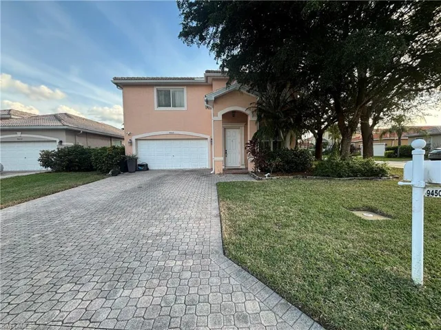 View of front of property featuring a front yard, stucco siding, decorative driveway, and an attached garage