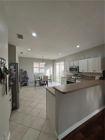 Kitchen with white cabinets, stove, recessed lighting, refrigerator, and pendant lighting