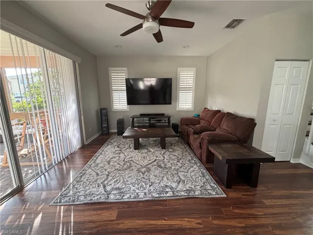 Living room with dark wood finished floors and a ceiling fan