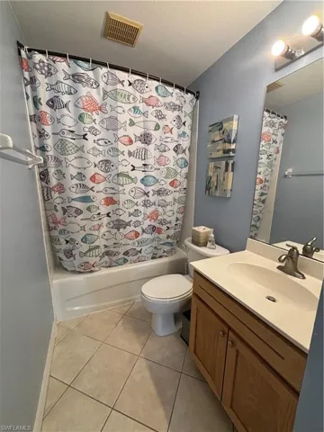 Bathroom with vanity, light tile patterned floors, shower / bath combo, and a textured ceiling