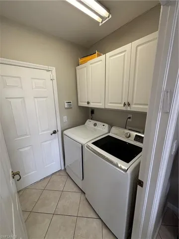 Washroom featuring light tile patterned floors, cabinet space, and independent washer and dryer