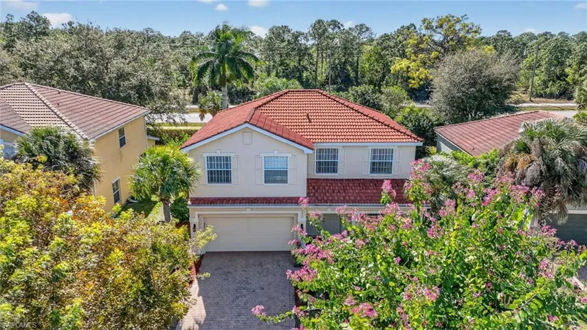 Mediterranean / spanish-style home featuring a tiled roof, stucco siding, a garage, and driveway
