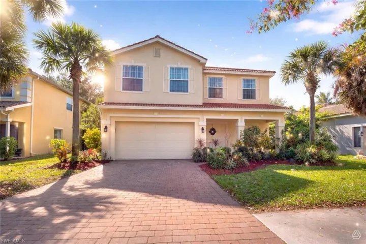 Two-story stucco home featuring a tile roof and decorative window shutters