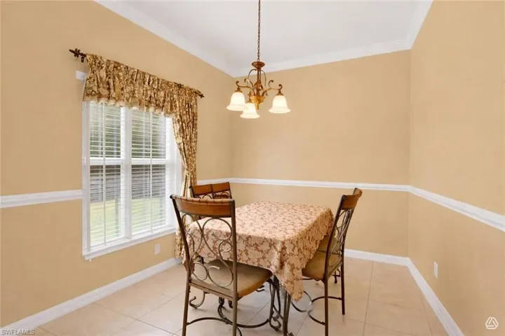 Dining area featuring a window with white blinds, crown molding, chair rail molding, and tile flooring
