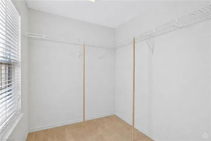 Walk-in closet featuring built-in wire shelving, hanging rods, and a window with horizontal blinds