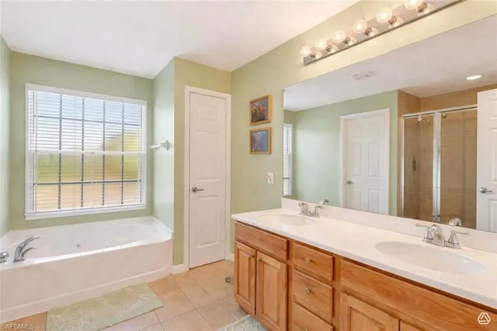 Bathroom featuring a dual vanity with light-tone wood cabinetry, white countertops, and undermount sinks